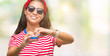 Young beautiful arab woman wearing sunglasses over isolated background smiling in love showing heart symbol and shape with hands. Romantic concept.