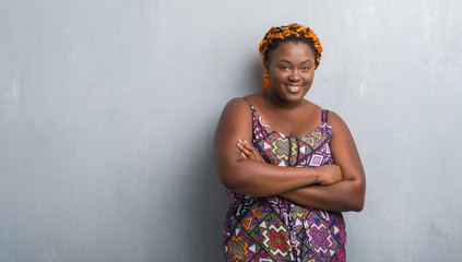 Poster - Young african american woman over grey grunge wall wearing orange braids happy face smiling with crossed arms looking at the camera. Positive person.