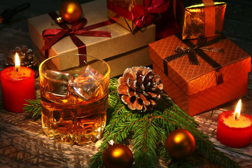 Wall Mural - Cognac or whiskey in glass. Christmas balls, gift boxes and candles. New Year's tree, balls and glass with alcohol.