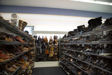 Isolated View Of Neutral Colored Womens Pumps, Shoes, Sandals And Purses On Thrift Store Shelves And Display - Focus On Purse Display On Back Wall