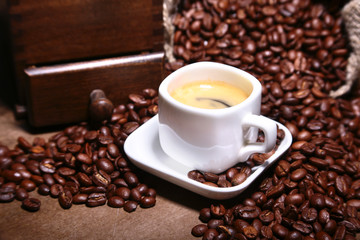 Wall Mural - Fresh roasted coffee beans in burlap sack, coffee cup and grinder on dark background.