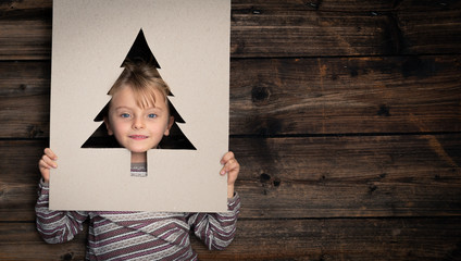 Wall Mural - Text or logo empty copy space,vertical top view dark vintage wood.Happy child girl in homewear with cardboard tree pine.Childhood concept.Xmas winter holiday season party social media card background 