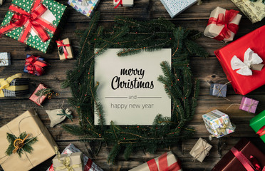 Wall Mural - Merry Christmas and happy new year greetings in vertical top view vintage wood.Pine branches,ribbons, lights,gift present boxes decorated frame.Xmas winter holiday season social media card background 