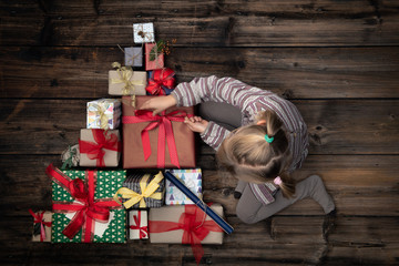 Wall Mural - Child girl in homewear in vertical top view vintage wood with christmas tree pine made of gift present boxes.Xmas winter holiday season party social media card background