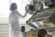 Side view portrait of female factory worker wearing clean white coat standing by machine units at packaging line, copy space