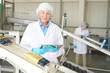© Seventyfour - Portrait of senior woman controlling  production process at modern food factory and looking at macaroni bags sliding down conveyor belt, copy space