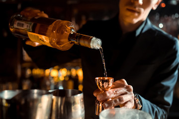 Wall Mural - The bartender strains a cocktail in a glass at a nightclub, beach, pub, restaurant