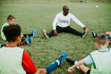 Wall Mural - Football coach stretching with junior players