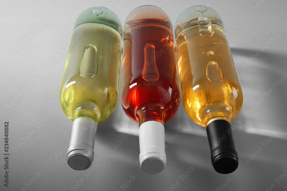 Bottles with different kinds of wine on grey background
