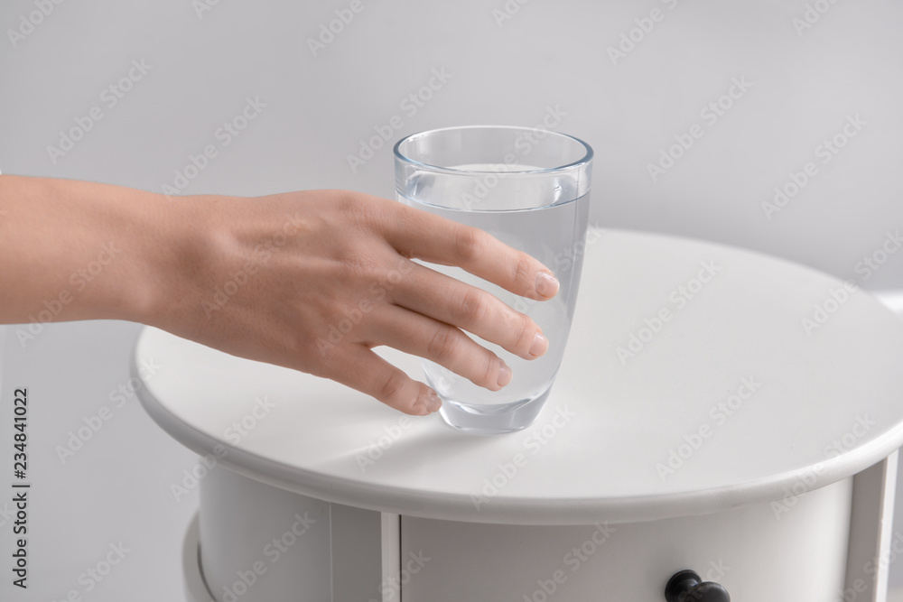 Woman taking glass of fresh water from white table