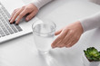 © Pixel-Shot - Woman drinking fresh water while working on laptop