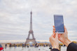 © astrosystem - Girl using cellphone with Paris city background and Eiffel tower.