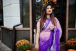 © AS Photo Family - Indian hindu girl at traditional violet saree posed at street against door of restaurant with autumn mood and pumpkins.