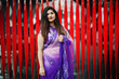 © AS Photo Family - Indian hindu girl at traditional violet saree posed at street against red background.