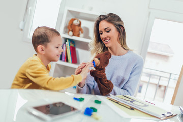 Little boy during lesson with his speech therapist. Learning through fun and play