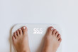 © Dina Photo Stories - Young woman feets on weight scale at home. Dieting, nutrition. Close-up, copy space