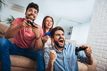 Group of young friends play video games together at home.