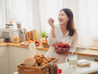 © potsawat - asian woman eating fruit in the kitchen