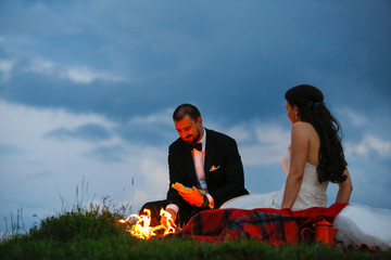 Beautiful wedding couple posing in nature with fire