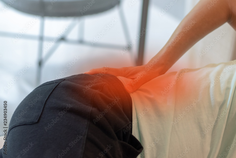 Hip joint pain concept. Man hand on his low back with red spot as suffer from injury or arthritis - obrazy, fototapety, plakaty 