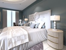 The Modern Design Of The Bedroom With A Large White Bed And A Stool With A Dressing Table Nearby. Dark Walls Light Furniture, White Marble Floor.