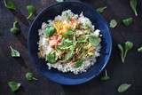 Fototapeta  - Ryż z warzywami. Potrawa warzywna na niebieskim talerzu z listkami sałaty i zielonym porem.