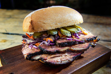 Detail Of Brisket Sandwich With Cucumber And Coleslow On Cutting Board