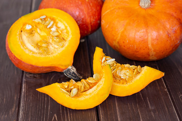 Canvas Print - Group of two whole one half two slices of fresh red kuri pumpkin hokkaido variety on brown wood