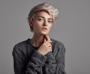 Fashion portrait of young woman with blond short hair isoalted on gray background