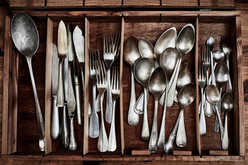 A vintage service cutlery inside a rustic wooden box.