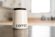 Close Up Bright Modern Stock Photo Of Cute White Coffee Bean Container On Top Of Wooden Counter Top With Elegant Kitchen Blurred In Background Of With Natural Light