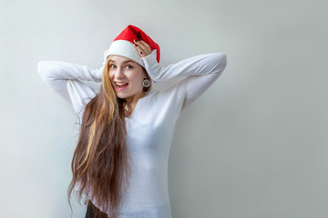 Beautiful girl with long hair in red Santa Claus hat isolated on white background looking happy and excited. Young woman portrait, true emotions. Happy Christmas and New Year holidays