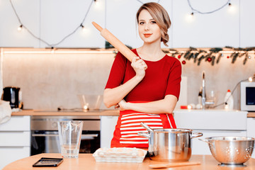 young housewife preparing Christmas dinner in the kitchen in red apron.