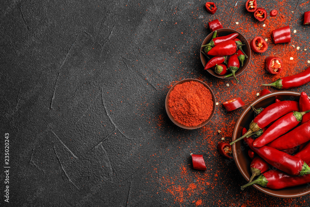 Flat lay composition with powdered and raw chili peppers on dark background. Space for text - obrazy, fototapety, plakaty 