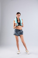 Wall Mural - Beautiful young woman in sportswear with towel on white background