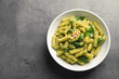 Plate of delicious basil pesto pasta and space for text on gray table, top view