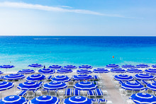 Blue Umbrellas And Chairs On Beach By Blue Sea, In Nice, France