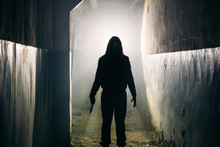 Silhouette Of Man Maniac Or Killer Or Horror Murderer With Knife In Hand In Dark Creepy And Spooky Corridor. Criminal Robber Or Rapist Concept In Thriller Atmosphere
