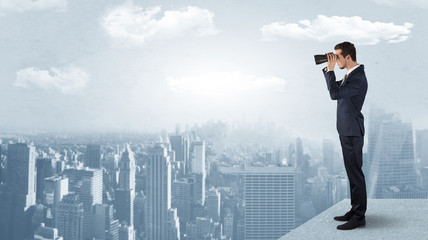 Wall Mural - businessman looking forward to a city with binoculars from skyscraper concept
