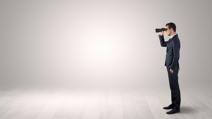 Wall Mural - businessman looking forward with binoculars in an empty space