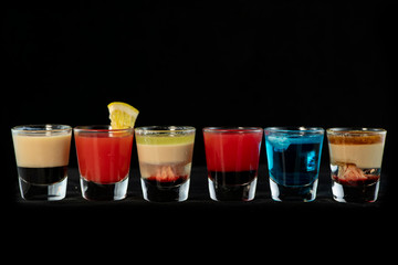 Mix alcoholic cocktail shots together with isolated black background