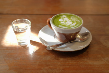 Wall Mural - hot matcha green tea with leaves latte art on wood table