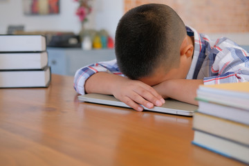 Wall Mural - lazy stressed young little asian kid boy  resting sleeping on desk. child fall asleep. children tired from studying in classroom.