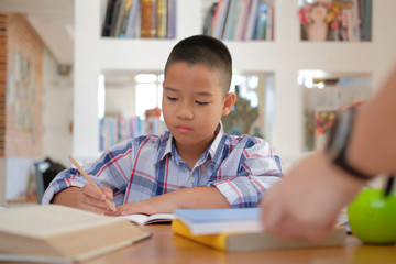 Wall Mural - little asian kid boy schoolboy writing drawing on notebook. child children doing homework.