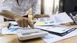 © Ngampol - Business woman accountant working and calculating financial data on graph documents, doing finance in workstation