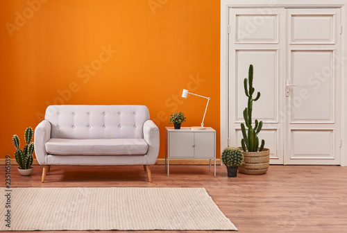 Fototapeta Living room sofa with orange background and white classic door.