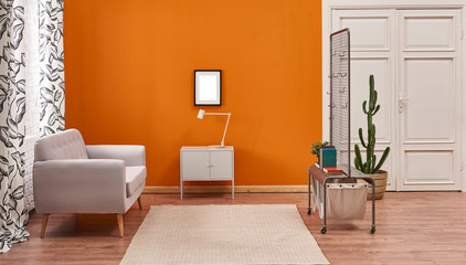 Living room orange wall grey cabinet white lamp frame and grey sofa. Metal unites with curtain.