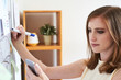© DragonImages - Young businesswoman drawing on whiteboard with marker while watching smartphone in office