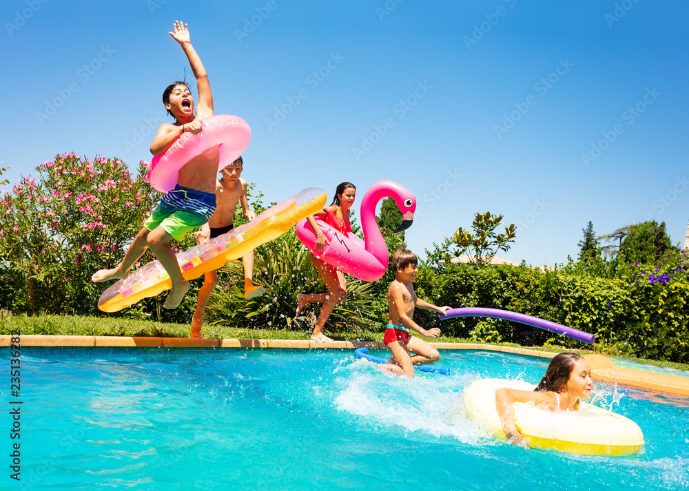 Happy friends jumping in pool on the vacations - obrazy, fototapety, plakaty 