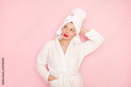 Fotografie, Obraz Beauty Young woman with red lips standing in the bath robe on the pink backgroun